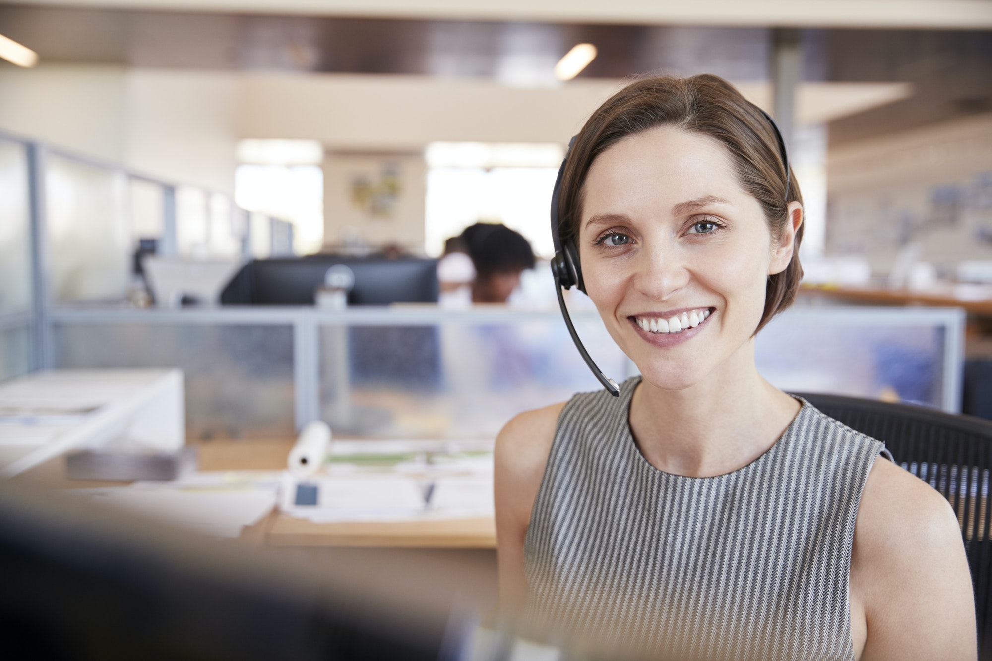 Young white woman working in a call centre smiling to camera